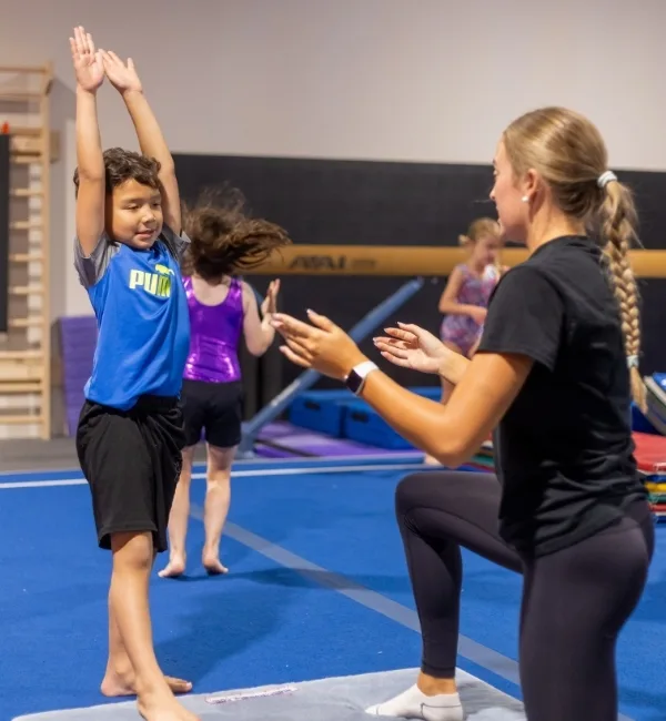 Gymnastics trainer helping a youth gymnastics athlete at a Haverford Y's Gymnastics Center