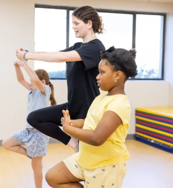 Gymnastics instructor teaching poses to youth gymnastics athletes inside studio