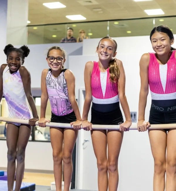 Youth gymnastics athletes hanging on uneven bar at Haverford Y's Gymnastics Center