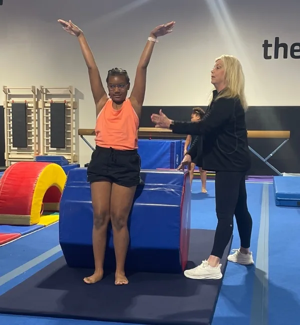 Gymnastics trainer helping youth gymnastics athlete tumble at Haverford Y's Gymnastics Center