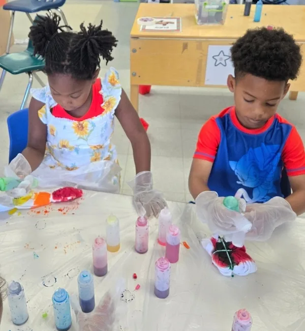 Children tie dying shirts inside a classroom