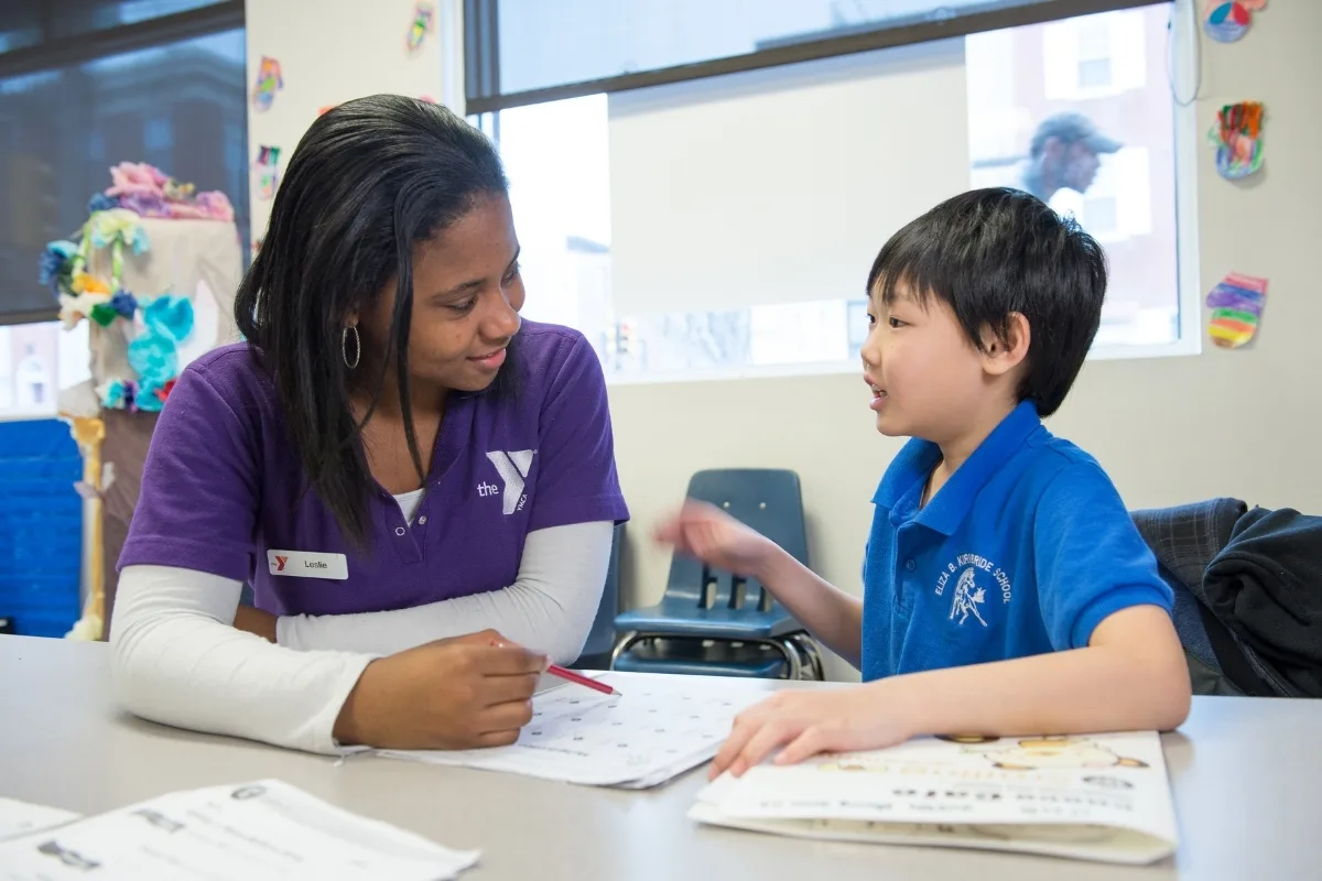 Teaching staff member helping a child with schoolwork in a classroom