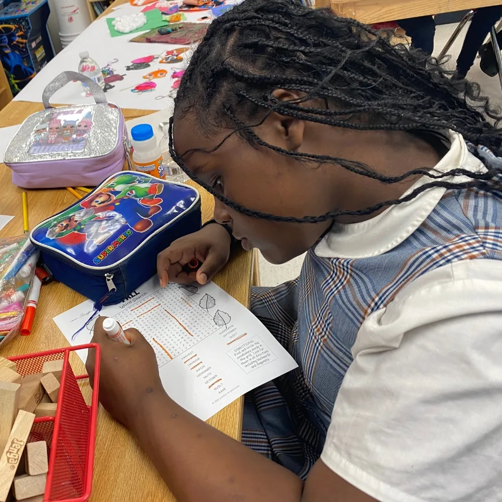 Child drawing on schoolwork in classroom