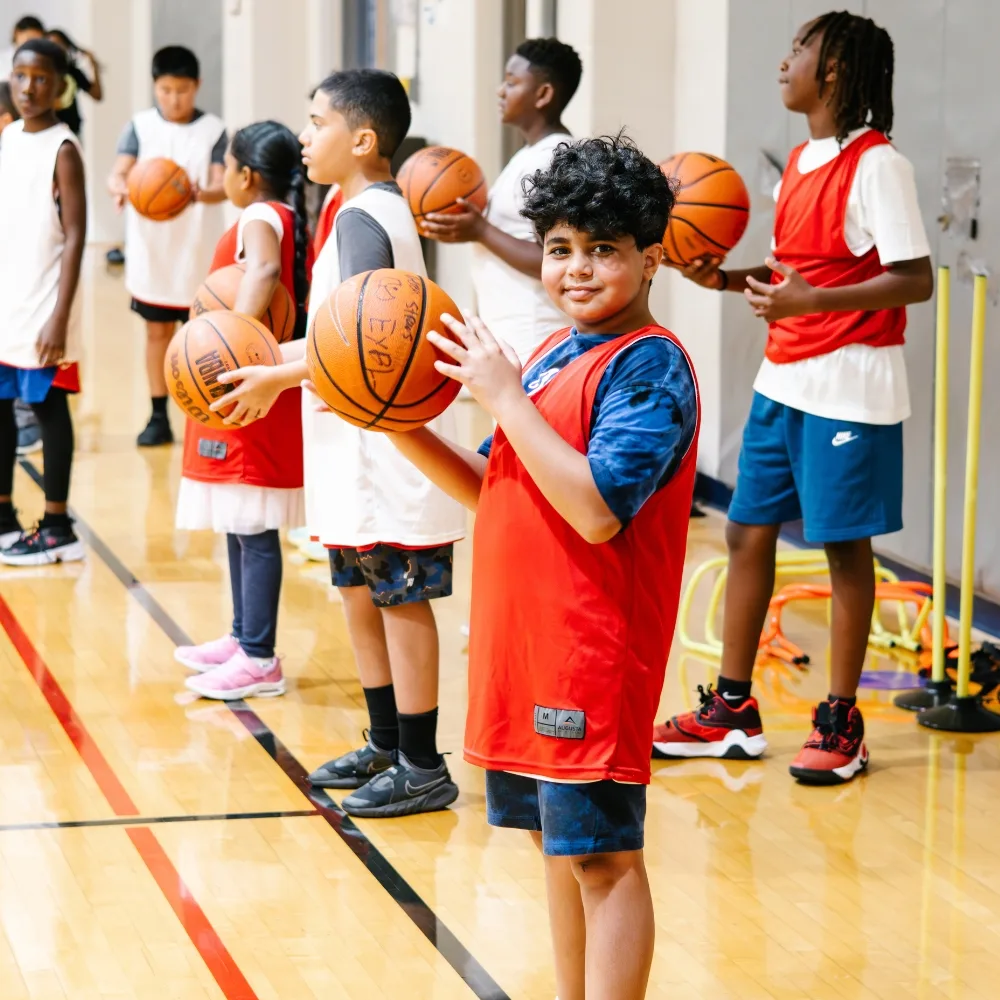 Youth practicing basketball on indoor basketball court