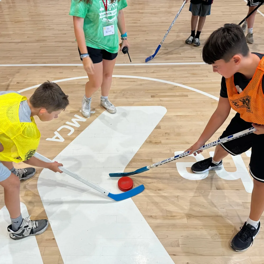 Children playing indoor hockey inside gymnasium during Camden Y's CATCH program