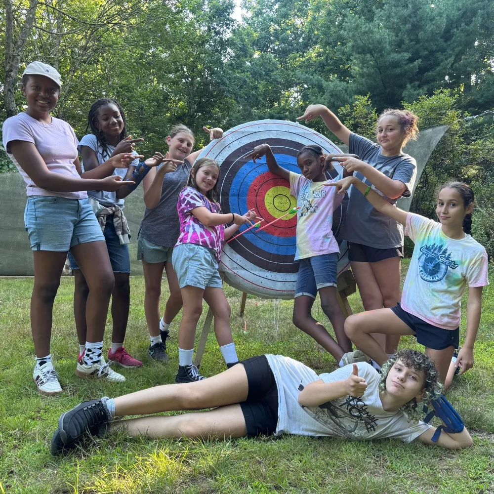Campers posing in front of an archery target outdoors