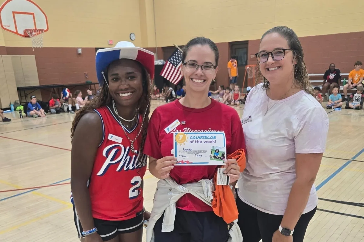 Camp counselors smiling inside gymnasium