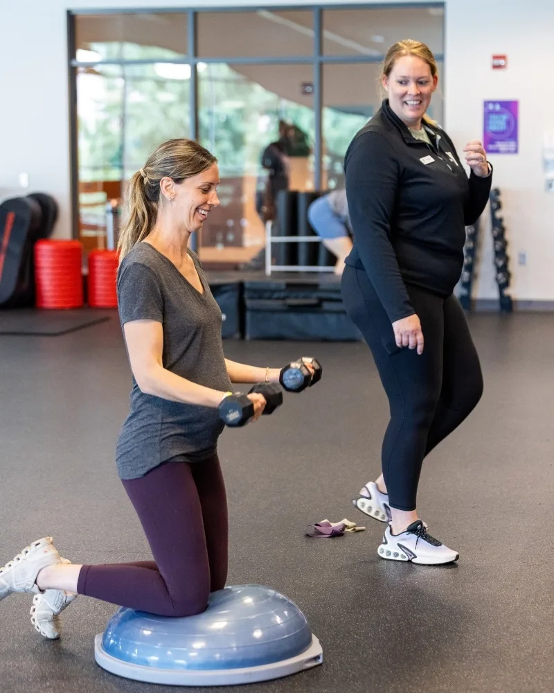 Personal trainer training pregnant member during Maternal Wellness group exercise class in a studio