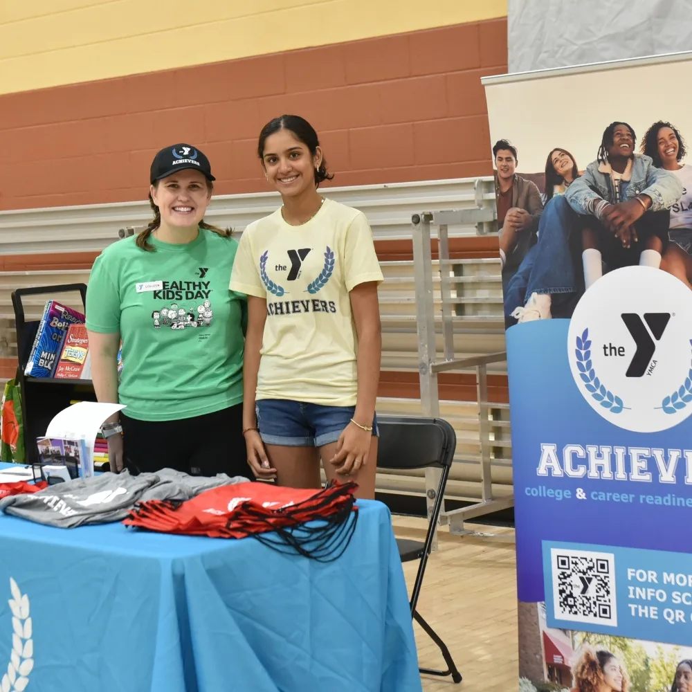 Y staff member and teen tabling at Y Achievers event inside gymnasium