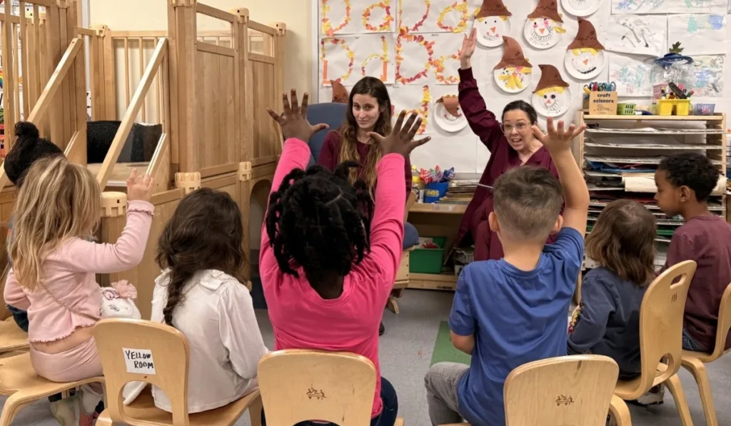 Early Leaning Center staff members and children sitting in a circle inside classroom