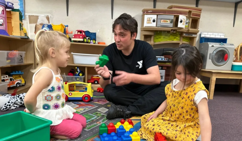 Early Learning Center staff member and children playing with blocks inside classroom