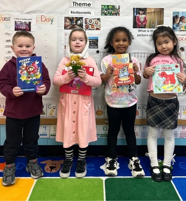 Children holding books inside classroom