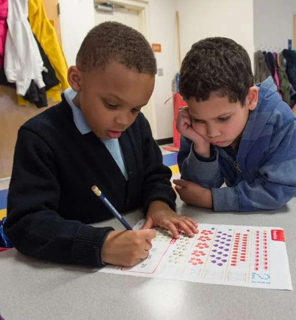 Children writing on school work inside classroom