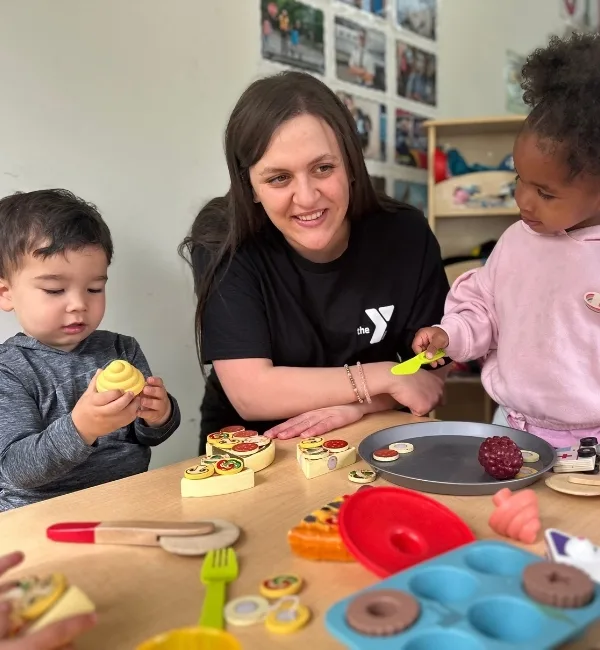 Early Learning Center staff member and children playing with food toys inside classroom