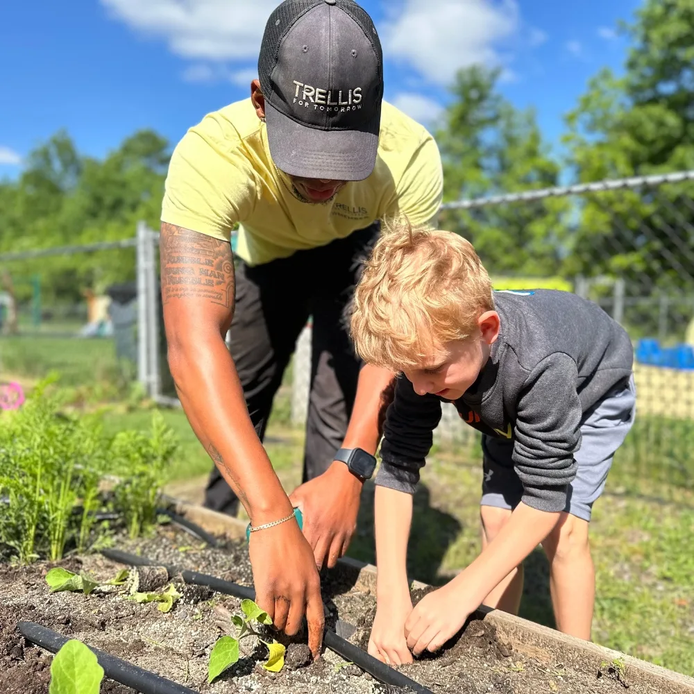 Mentor and child digging in planter outside at Phoenixville Y's community garden