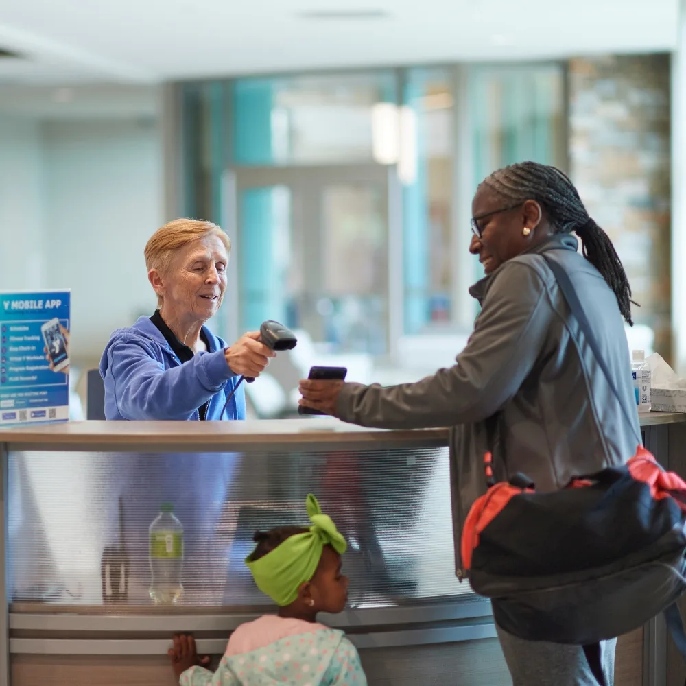 Y staff member scanning a member in at the front desk