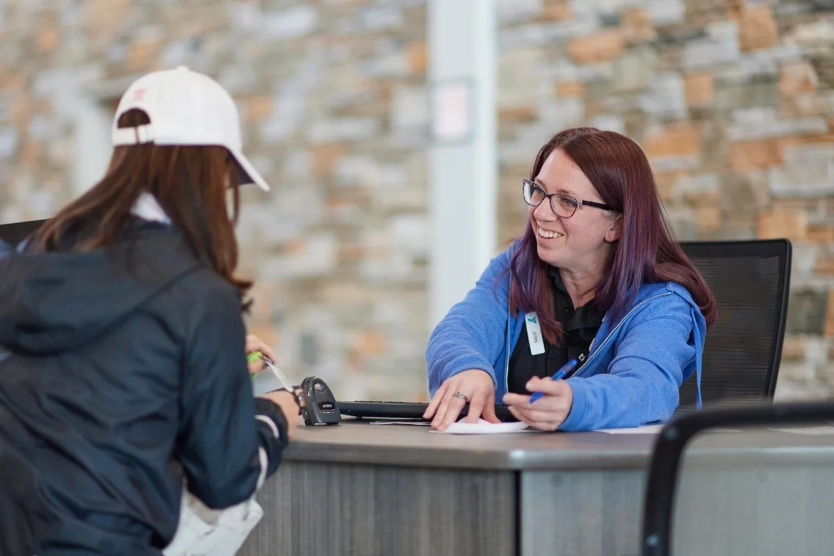 Y staff member helping member at the front desk