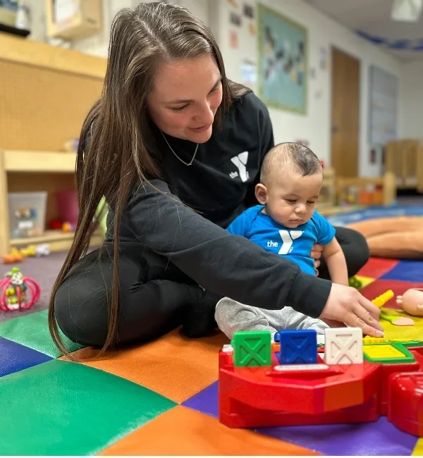 Early Learning Center staff member helping a child play with a toy