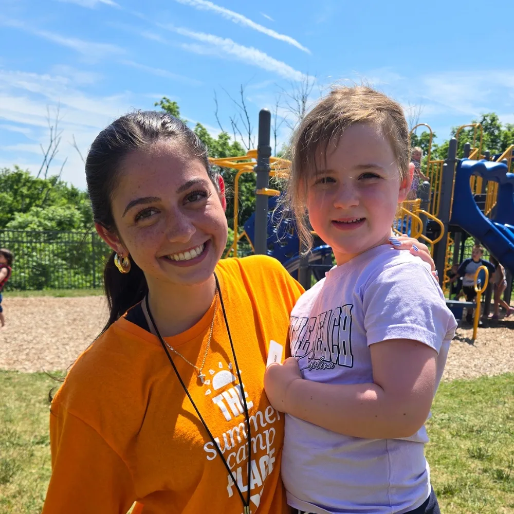 Summer camp counselor with a camper on playground