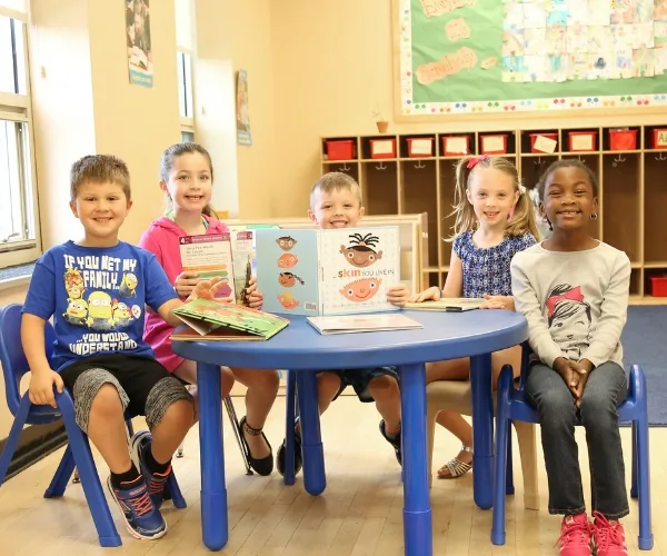 Group of children reading a book inside a classroom