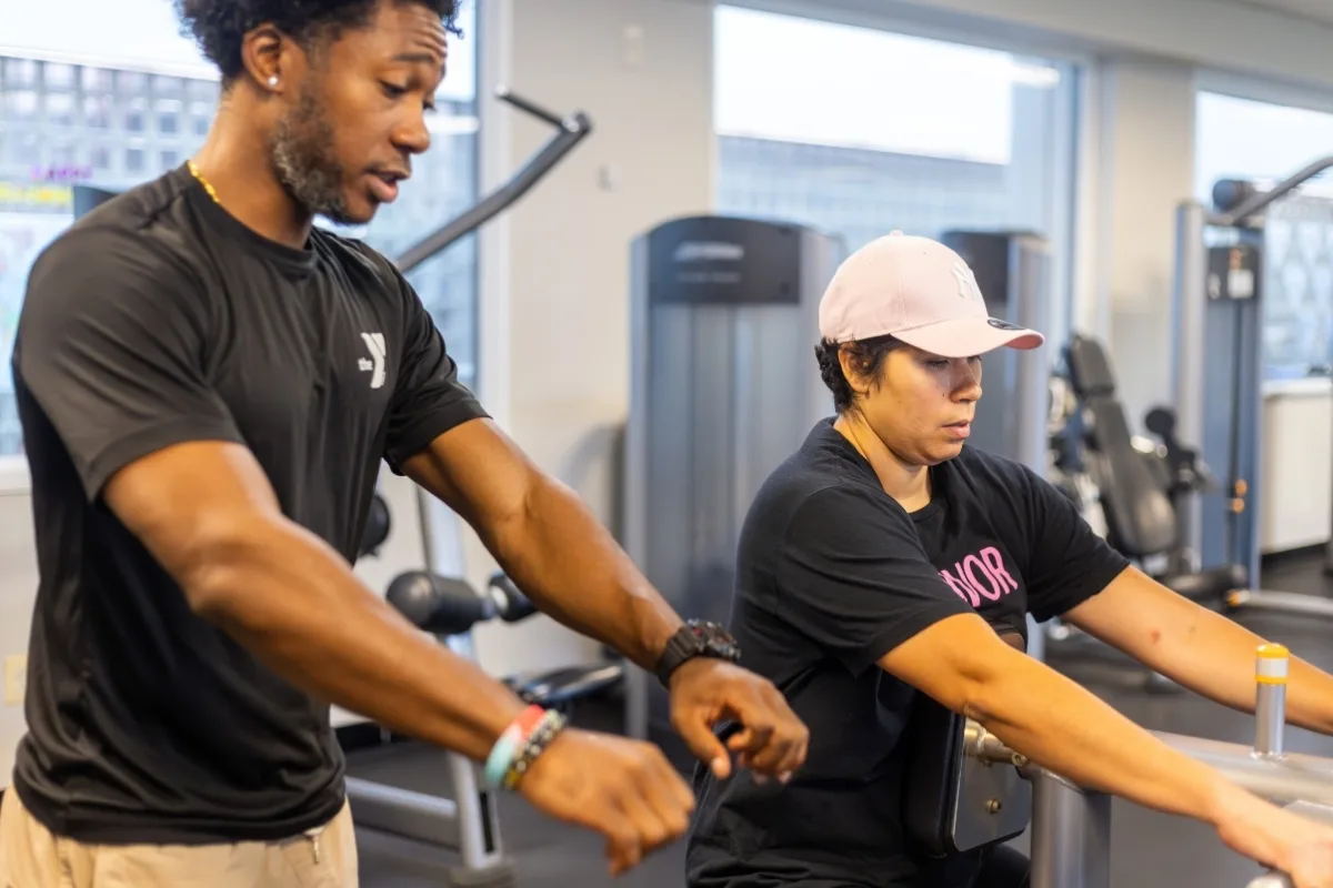 Personal trainer helping a member on the rowing machine inside fitness center