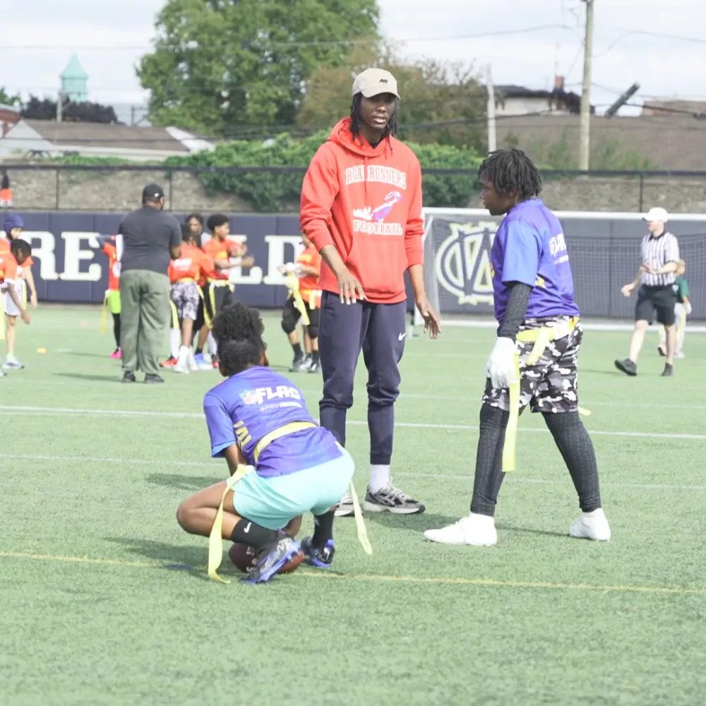 Youth playing flag football on turf outside