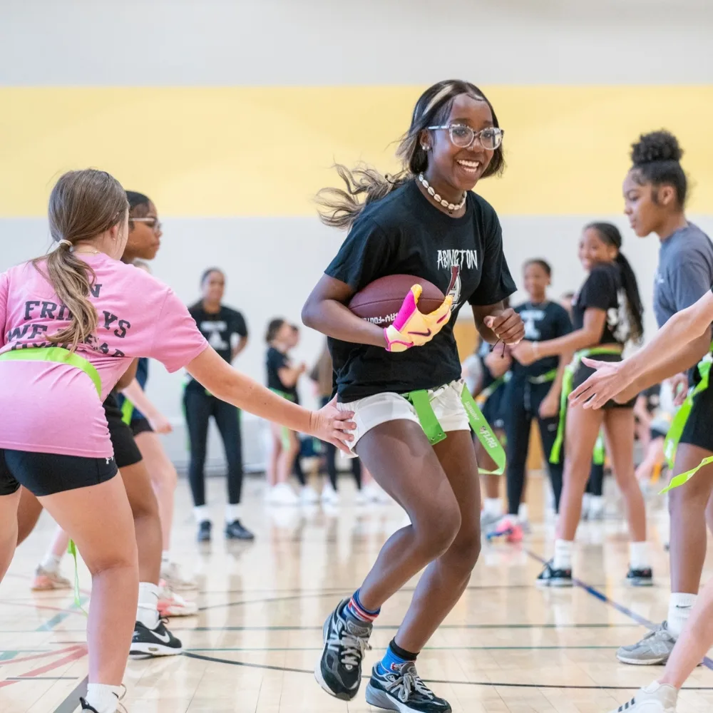 Youth playing flag football inside gymnasium