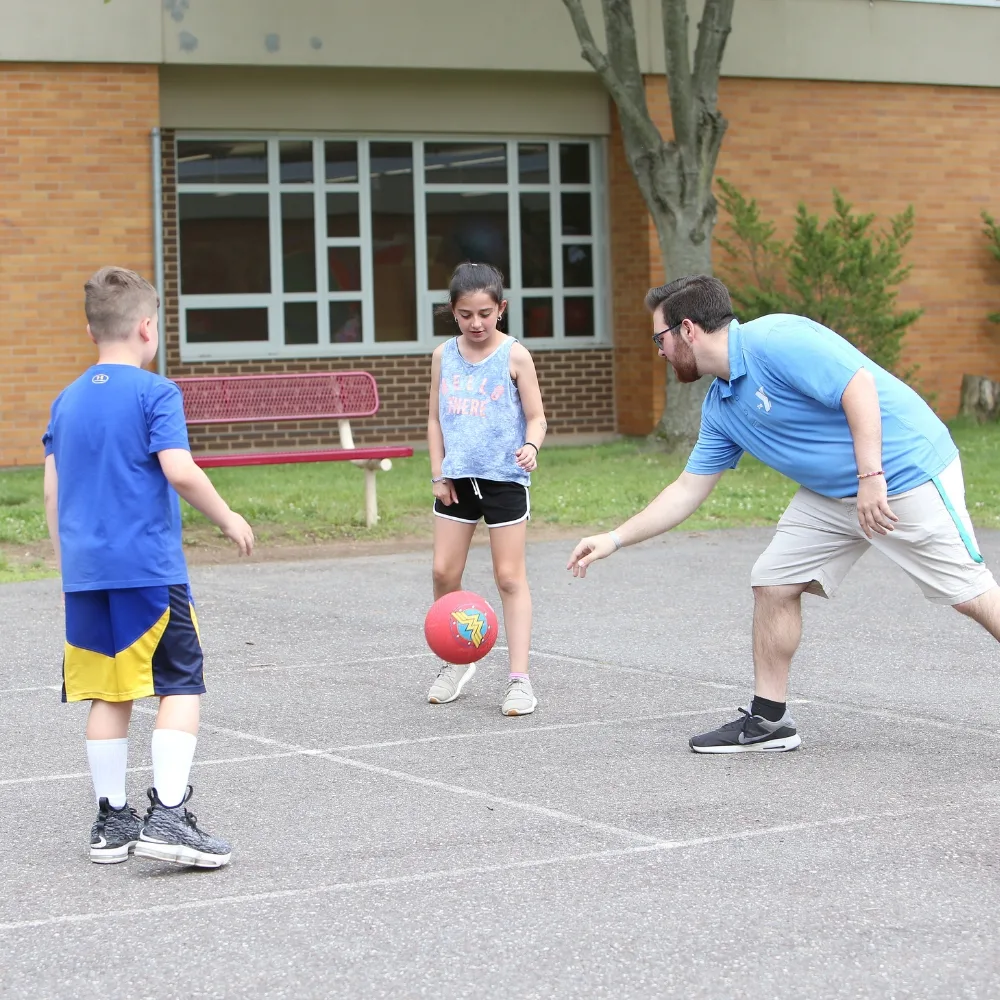 Teaching staff playing four square with children outdoors