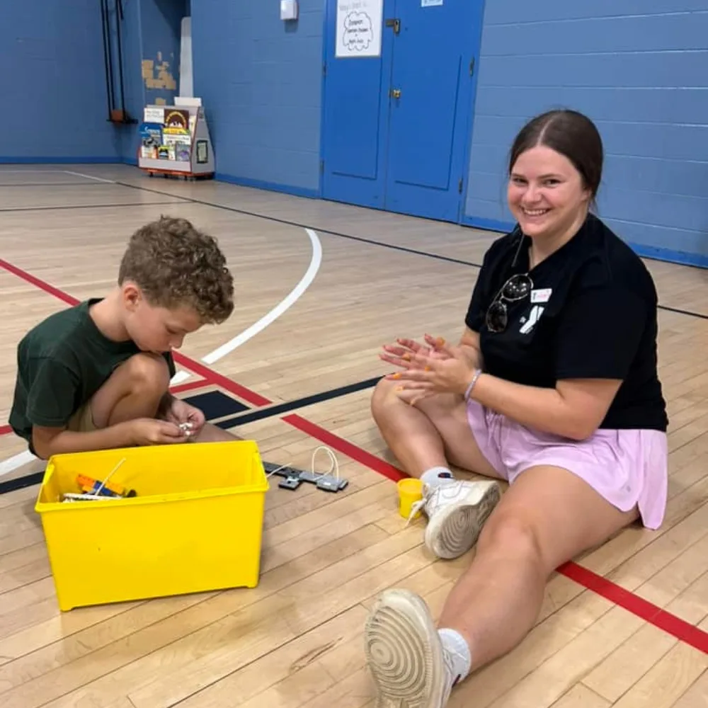 Teaching staff and child playing with toys in gymnasium