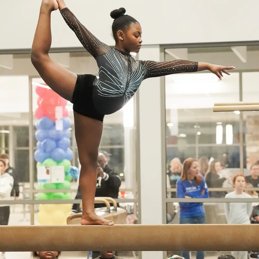 Greater Philadelphia Y's youth gymnastics athlete posing on a balance beam