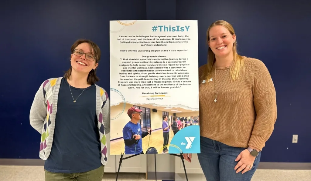 Y staff members standing by an informational sign