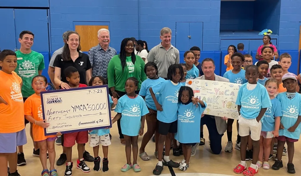 Summer camp staff and campers accepting donation inside gymnasium