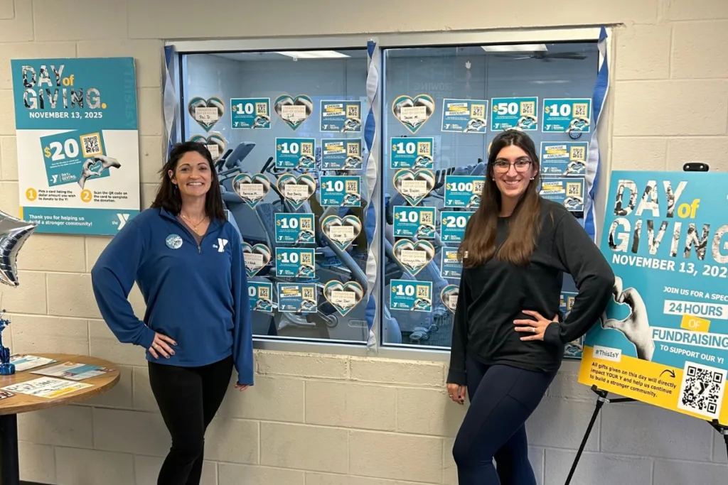 Y staff members standing near informational sign about Day of Giving