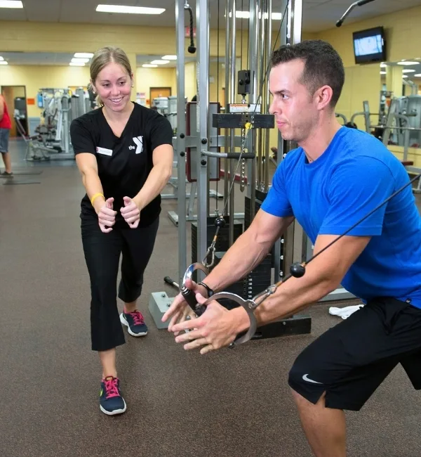 Personal trainer helping a member on weight lifting equipment