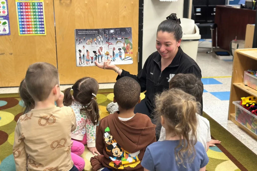 Early Learning Center staff member reading to a group of children inside a classroom