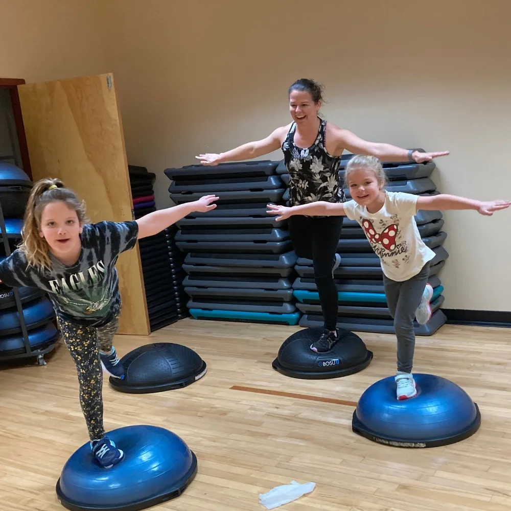 Members balancing on exercise equipment in a studio