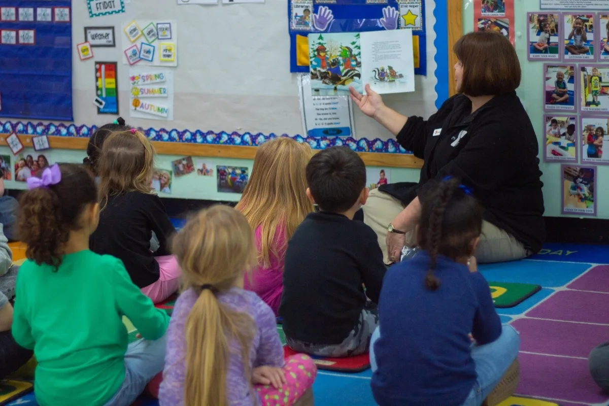 Early Learning Center staff member reading to a group of children inside a classroom
