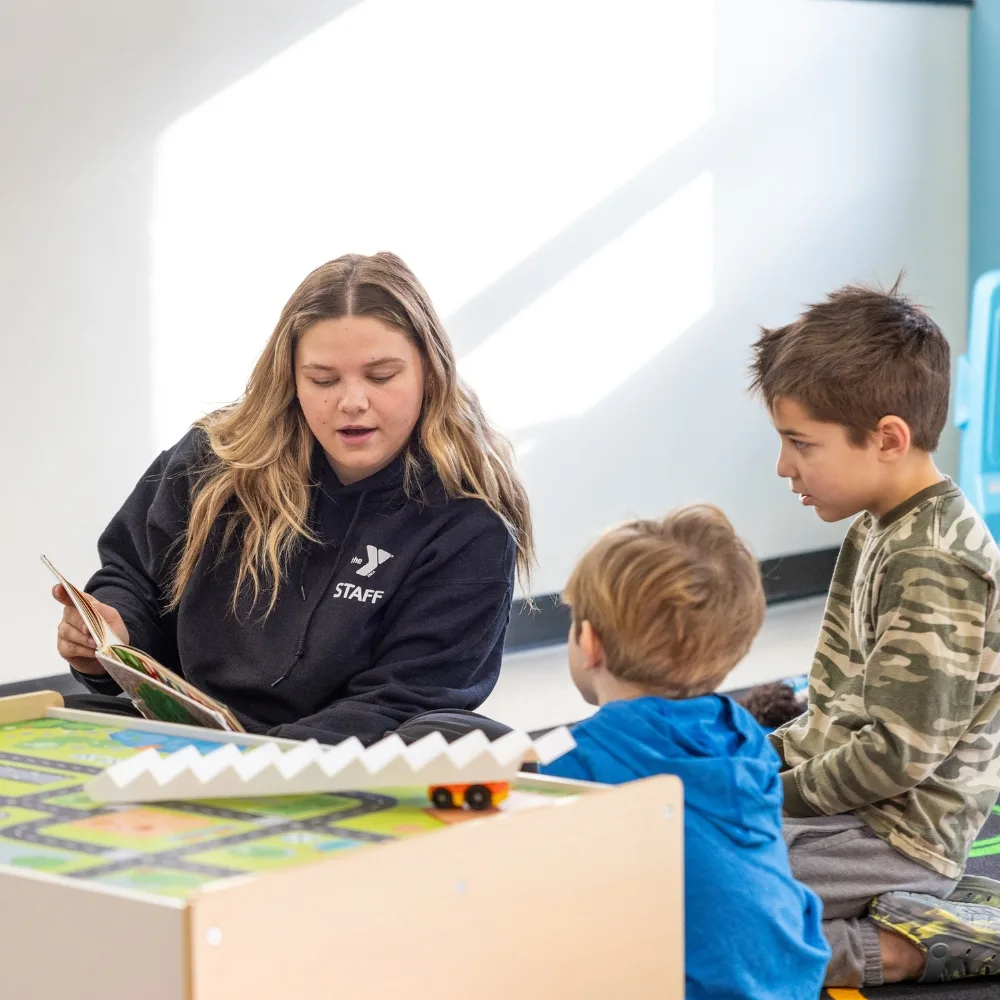 Y staff member reading a book to children in KidZone area