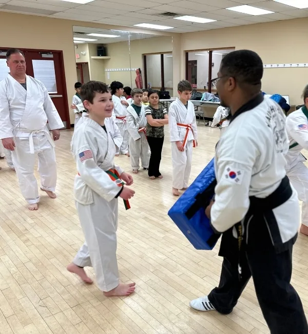 Youth practicing martial arts kicking with coach in studio