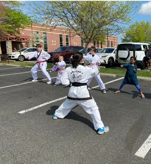 Youth practicing martial arts with coach in parking lot outdoors