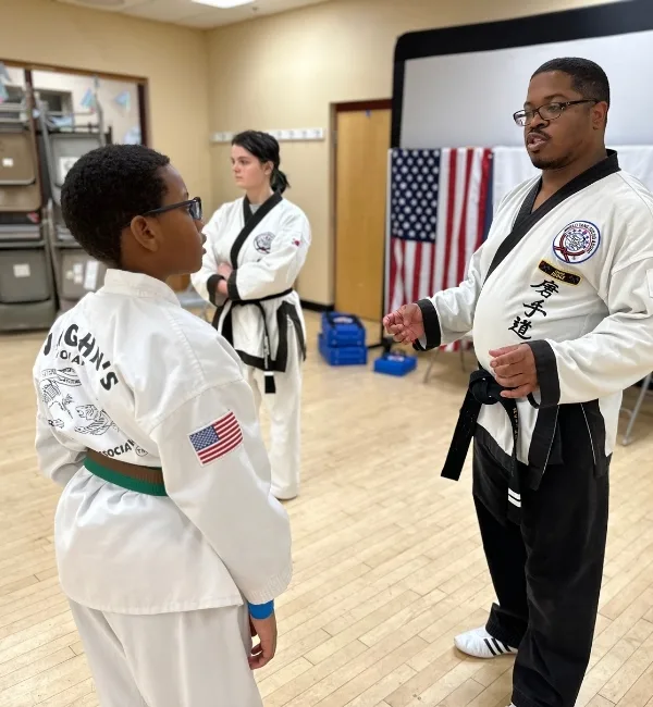 Martial arts coach speaking to youth inside studio