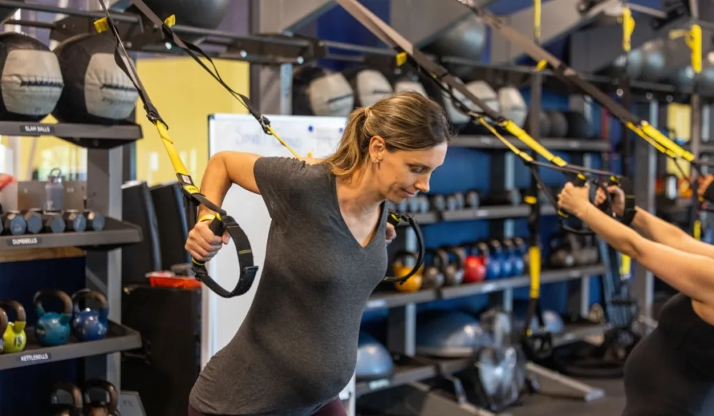 Maternal Wellness group exercise class using TRX equipment inside fitness center