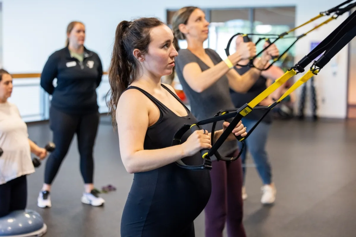 Maternal Wellness group exercise using TRX equipment inside fitness center