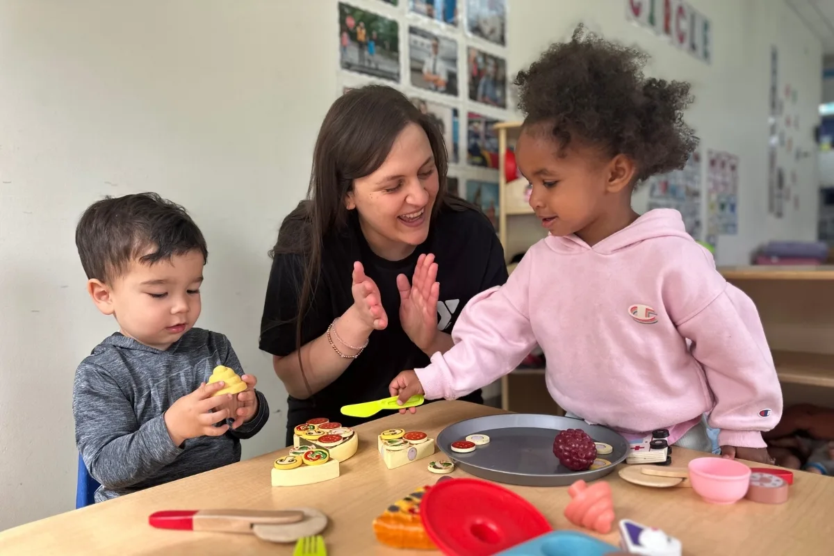 Pre-K staff member and children playing with toys in classroom