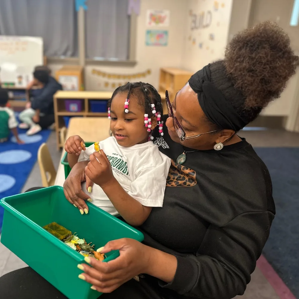 Pre-K staff member and child playing with toys in classroom