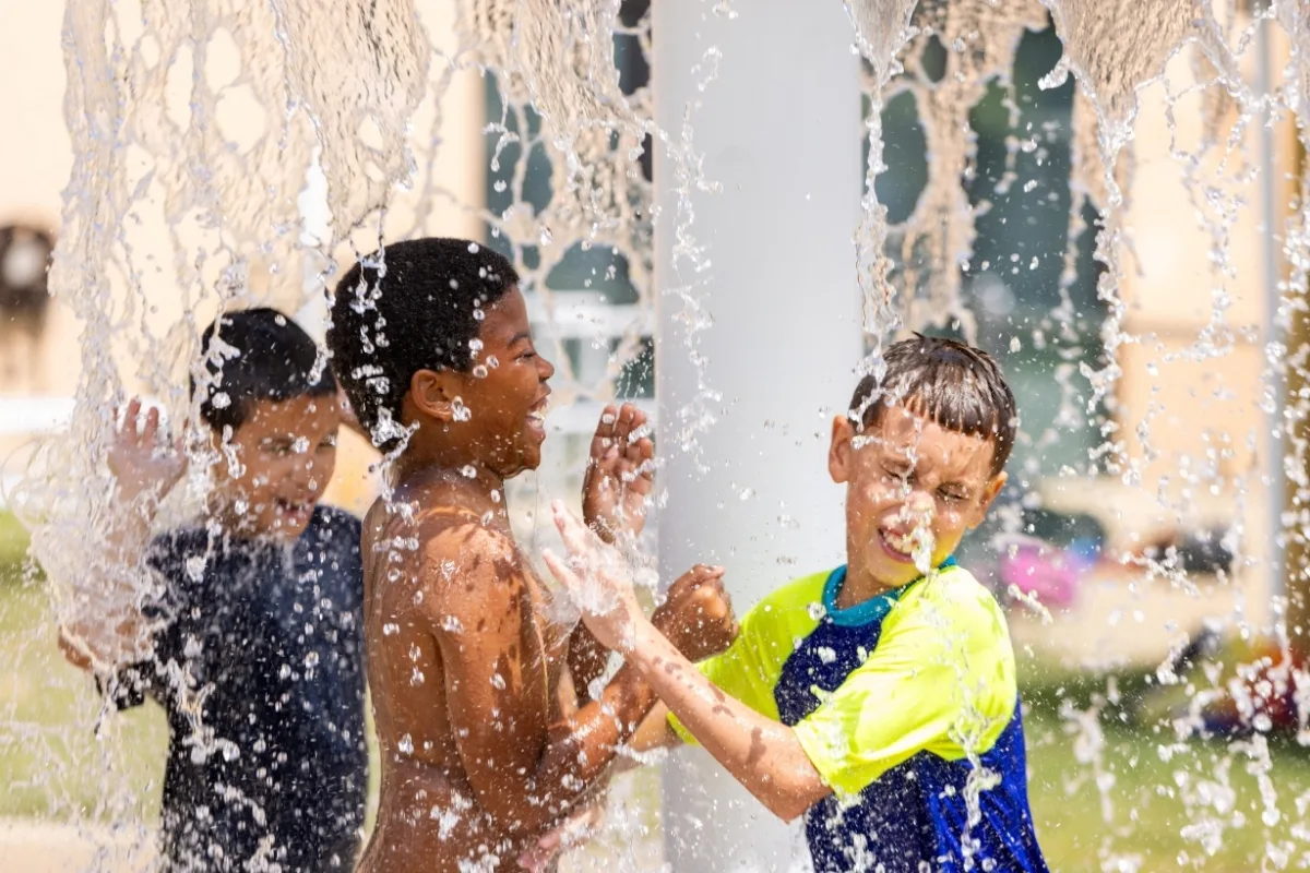 Campers playing under outdoor pool splash area at Northeast Family Y's summer camp
