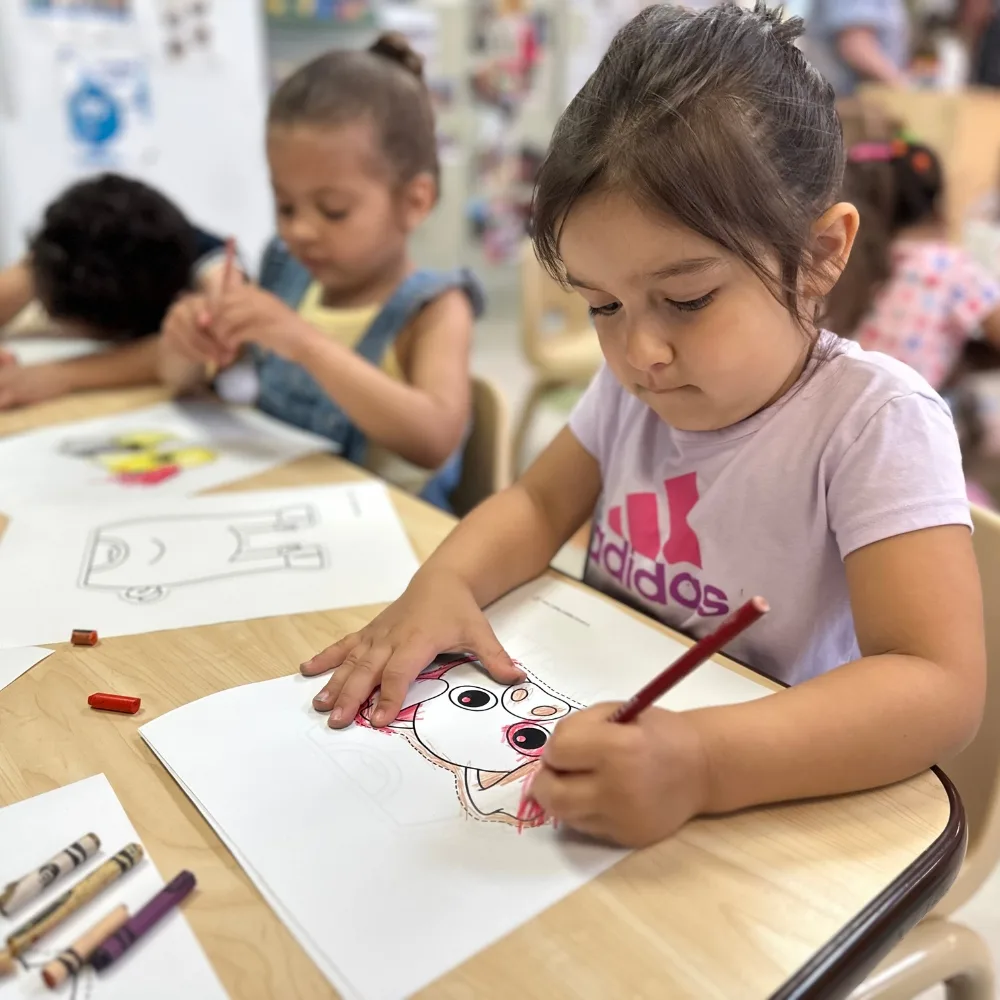 Children coloring on paper in classroom