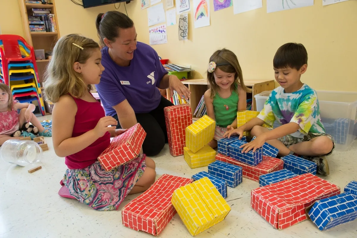 Group of children and Pre-K staff member playing with blocks in a classroom