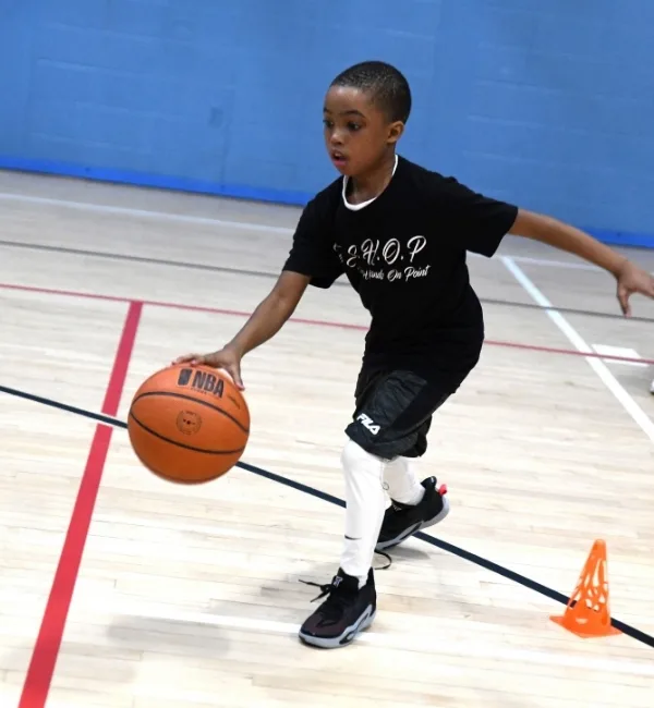 Child playing basketball on court