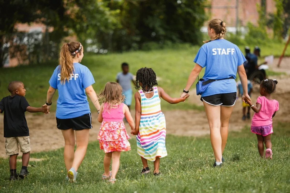 Camp counselors holding hands with campers
